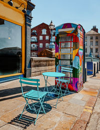 Chair and tables near a multi coloured phone box for pride month in leeds, united kingdom. 