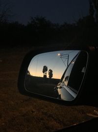 Reflection of man photographing car on side-view mirror