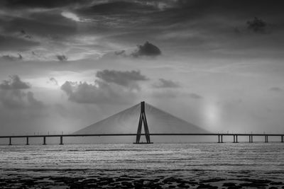 Bridge over calm sea against sky