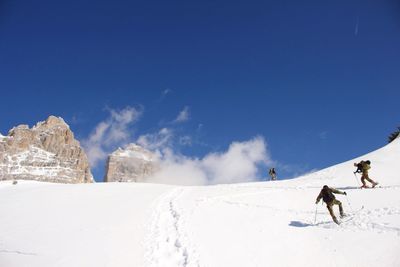 Low angle view of people skiing on snow covered landscape