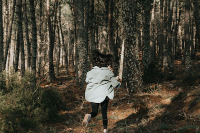 Rear view of woman standing in forest