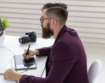 Side view of young man sitting on table