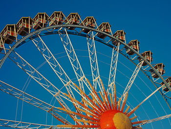 Low angle view of ferris wheel against clear blue sky