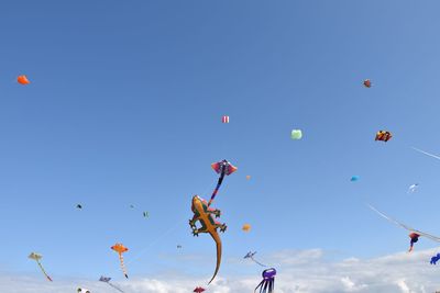 Low angle view of balloons flying against blue sky