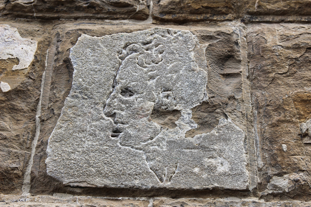 FULL FRAME SHOT OF STONE WALL WITH CARVING