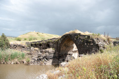 Bridge over river amidst land against sky