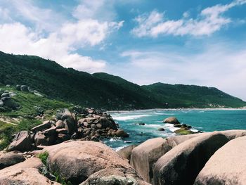 Scenic view of sea by mountains against sky