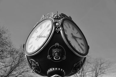 Low angle view of clock against bare trees