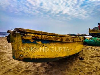 Close-up of boat moored on beach against sky