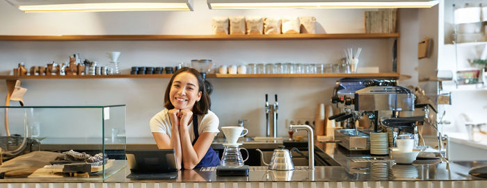 Portrait of young woman standing in kitchen