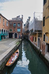 Canal amidst buildings in city against sky