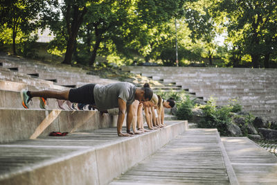 Team of multiracial male and female friends doing push-ups on steps