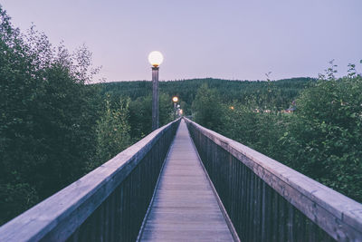 Footbridge amidst trees against clear sky