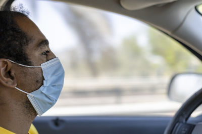 Close-up portrait of an middle eastern msn driving with a face mask