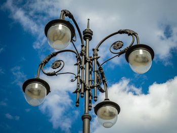 Low angle view of street light against cloudy sky on sunny day