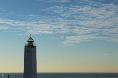 Lighthouse by sea against sky