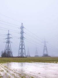 Electricity pylon on field against sky