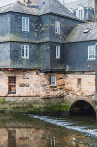 Arch bridge over river by old building