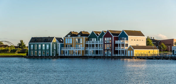 Colorful houses by river against clear sky