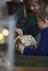 Siblings eating gingerbread house on table