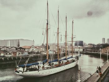 Boats moored at harbor against sky in city