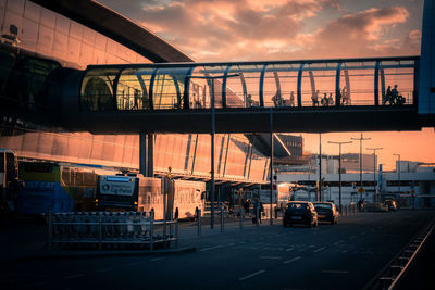 Train on bridge in city against sky during sunset