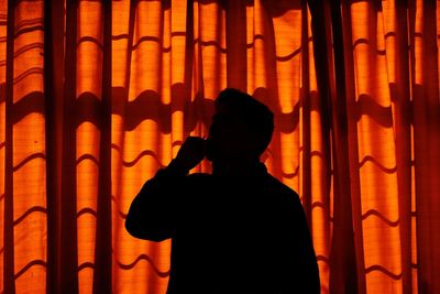 Silhouette man standing against curtain