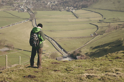 Full length rear view of hiker standing against landscape