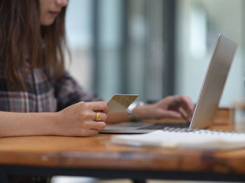 Midsection of woman using mobile phone on table