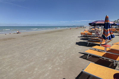 Table and umbrellas at beach against clear blue sky on sunny day