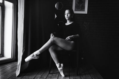 A young gentle and thoughtful ballerina poses in the interior and at the window