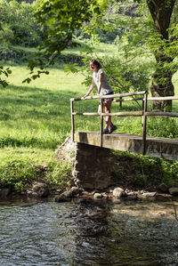 Fit woman standing in a wooden bridge and looking into the fores