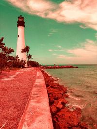 Lighthouse by sea against sky