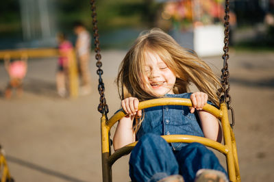 Portrait of smiling girl on swing in playground