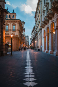 Street amidst buildings in city at dusk