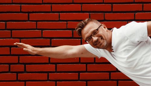 Portrait of mature man imitating superhero by red wall