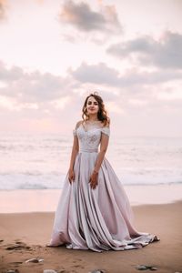 Portrait of woman standing at beach against sky