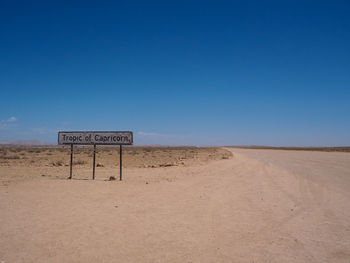 Information sign on desert against clear blue sky