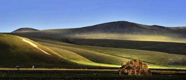 Hay bales pile on field against mountains