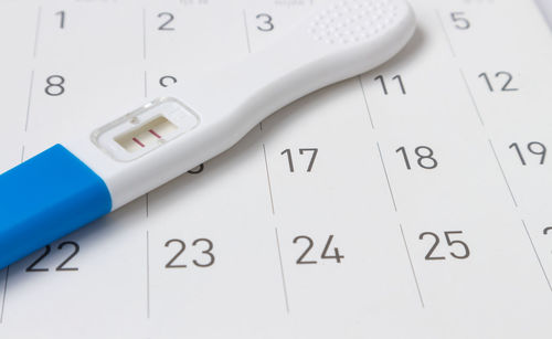 Close-up of pregnancy tester on calendar