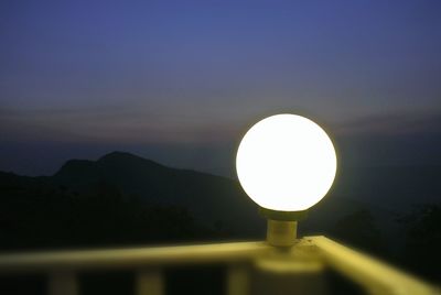 Illuminated light on silhouette mountain against sky at sunset