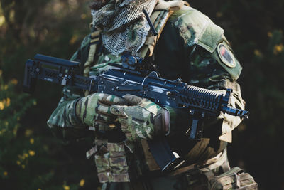 Midsection of soldier holding rifle