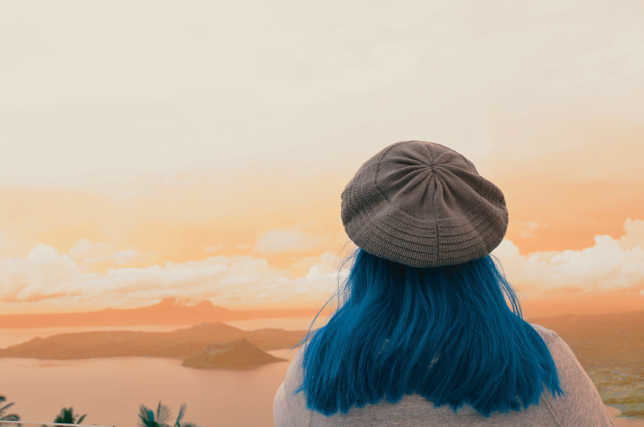 rear view, sky, sunset, real people, adult, women, cloud - sky, headshot, lifestyles, leisure activity, scenics - nature, beauty in nature, one person, hat, nature, hairstyle, hair, clothing, orange color, looking at view, warm clothing