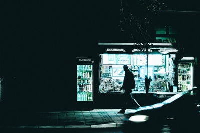 Silhouette man standing at illuminated railroad station