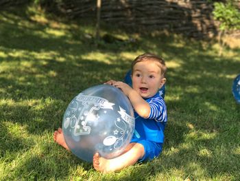 Boy with balloon on grass in field