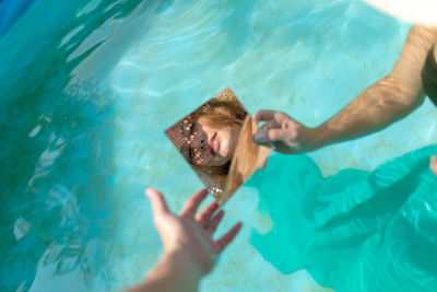 Reflection of woman in mirror while sitting in swimming pool