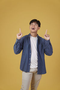 Full length of a boy standing against yellow background