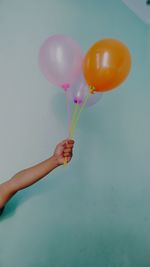 Low angle view of hand holding balloons