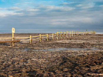 Wooden posts on beach against sky