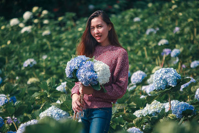 Portrait of smiling young woman standing against plants